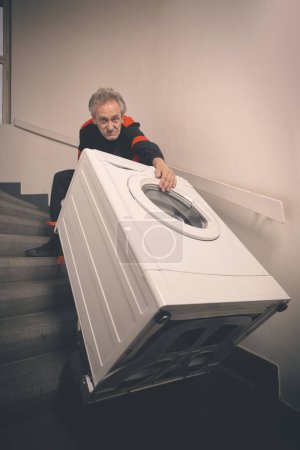 Téléchargez les photos : Homme plus âgé dans la machine à laver mobile globale sur le chariot dans la construction - en image libre de droit