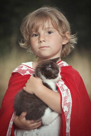 Foto de Caperucita roja con cesta de comida posando con gatito en el bosque - Imagen libre de derechos