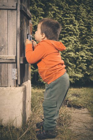 Téléchargez les photos : Petit garçon jouant dans le jardin comme un artisan dans la belle journée d'automne - en image libre de droit