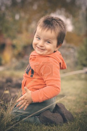 Téléchargez les photos : Petit garçon jouant dans le jardin comme un artisan dans la belle journée d'automne - en image libre de droit