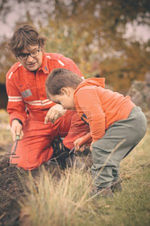 Foto de Niño pequeño con su padre jugando como artesano y jardinero en otoño - Imagen libre de derechos
