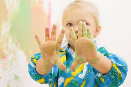 Photo for Little blonde girl handpainting clear white house wall - Royalty Free Image