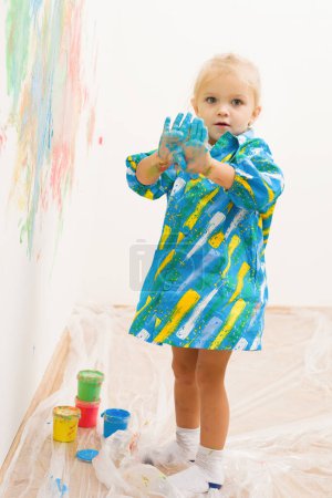 Photo for Little blonde girl handpainting clear white house wall - Royalty Free Image
