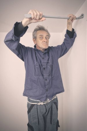 Téléchargez les photos : Homme plus âgé réparer les murs et le plafond dans un appartement vide - en image libre de droit