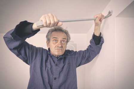 Téléchargez les photos : Homme plus âgé réparer les murs et le plafond dans un appartement vide - en image libre de droit