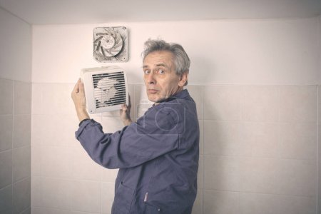 Foto de Hombre mayor desmontaje y limpieza de la unidad del ventilador en el baño - Imagen libre de derechos