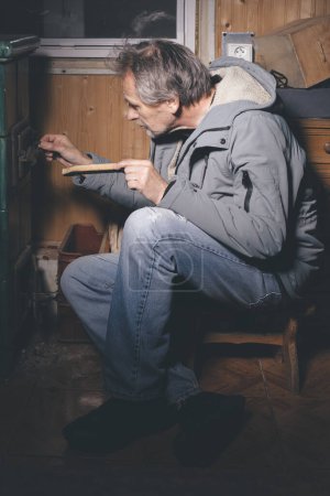Téléchargez les photos : Une personne âgée passe du temps en soirée dans son petit chalet - en image libre de droit