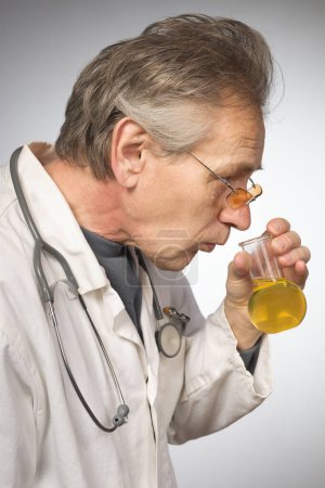 Foto de Médico practicante en bata médica tradicional retro determinar la enfermedad de la orina - Imagen libre de derechos