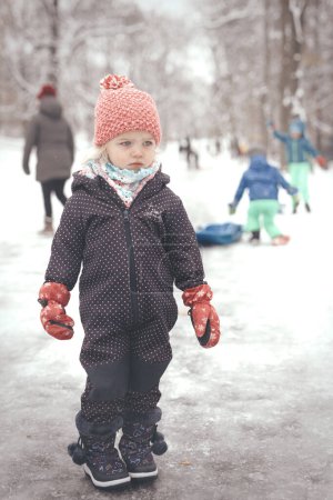 Photo for Two years old girl enjoying snow and ice in frozen city park - Royalty Free Image