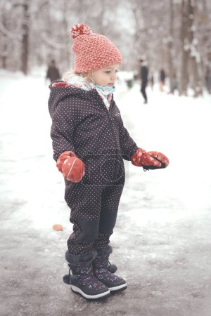 Foto de Chica de dos años disfrutando de nieve y hielo en el parque congelado de la ciudad - Imagen libre de derechos
