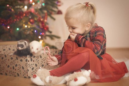 Foto de Chica en rojo en el momento del día de Navidad desempacar regalos cerca del árbol - Imagen libre de derechos
