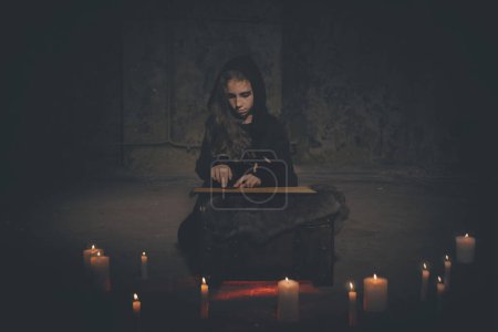 Téléchargez les photos : Jeune fille dans le style halloween convoquer des fantômes dans la maison vide - en image libre de droit