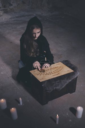 Téléchargez les photos : Jeune fille dans le style halloween convoquer des fantômes dans la maison vide - en image libre de droit