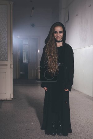 Photo for Young girl in halloween style summoning ghosts in empty house - Royalty Free Image