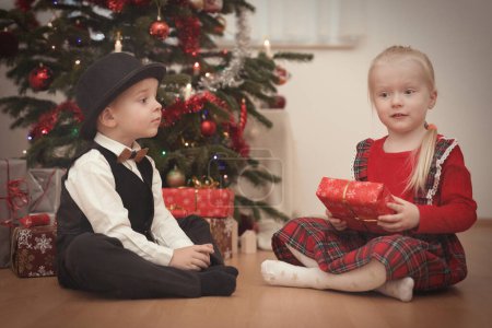 Photo for Children at time of christmas day unpacking gifts near tree - Royalty Free Image