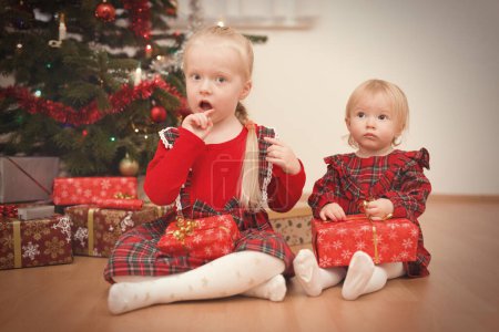Téléchargez les photos : Enfants au moment du jour de Noël déballer des cadeaux près de l'arbre - en image libre de droit