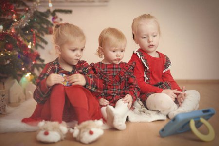 Los niños en el momento del día de Navidad desempaquetar regalos cerca del árbol