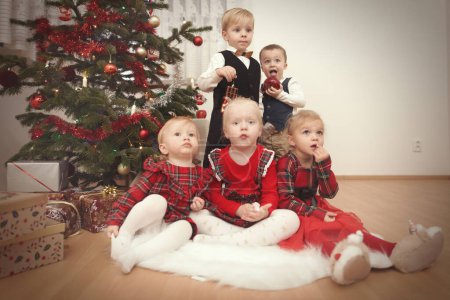 Foto de Los niños en el momento del día de Navidad posando juntos cerca del árbol - Imagen libre de derechos