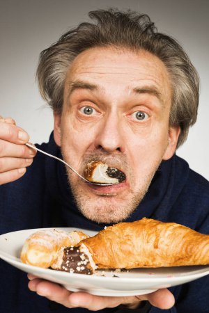 Téléchargez les photos : Homme plus âgé mangeant des pâtisseries sucrées et des gâteaux comme repas en studio - en image libre de droit