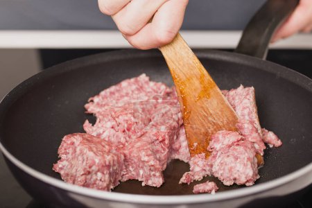 Photo for Older man in kitchen frying meat on pan for spaghetti receipe - Royalty Free Image