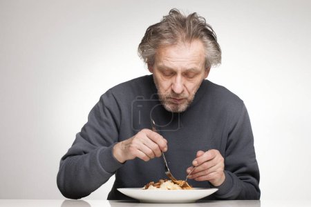 Photo for Older man eating spaghetti with minced meat, tomatoes and cheese - Royalty Free Image