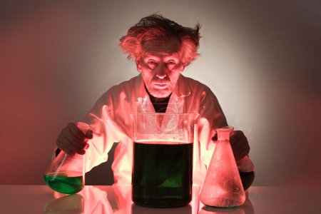 Téléchargez les photos : Un chimiste fou plus âgé prépare une expérience chimique avec des liquides - en image libre de droit