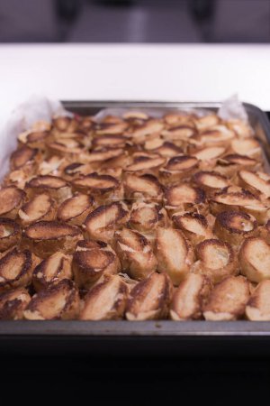 Téléchargez les photos : Cuisson du gâteau traditionnel aux pommes roulées aux noix, aux raisins secs et à la cannelle recouvert de neige blanche d'oeuf - en image libre de droit