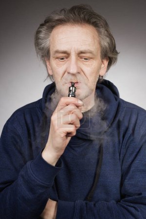 Foto de Hombre mayor con arrugas en la piel de la cara fumar cigarrillo electrónico - Imagen libre de derechos