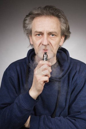 Photo for Older man with wrinkles on face skin smoking electronic cigarette - Royalty Free Image