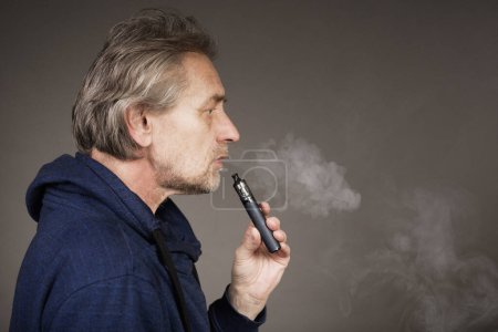 Photo for Older man with wrinkles on face skin smoking electronic cigarette - Royalty Free Image