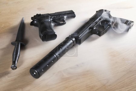 Téléchargez les photos : Plusieurs armes dans la brume sur la table en bois dans la chambre - en image libre de droit