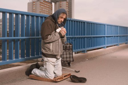 Un mendigo de la tercera edad en el paso elevado de la ciudad pidiendo algo de dinero