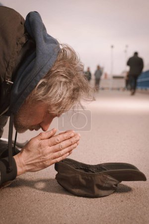 Foto de Un mendigo de la tercera edad en el paso elevado de la ciudad pidiendo algo de dinero - Imagen libre de derechos