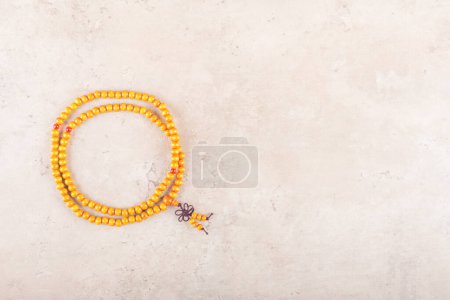 Photo for Japa wooden mala beads strands used for keeping count during mantra meditations on beige stone background. Top view, flat lay, copy space. spirituality practice of Buddhism. Praying and chanting - Royalty Free Image