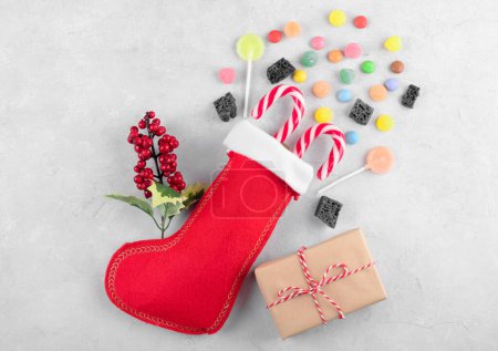 Red Epiphany Befanas stocking with sweet coal and candy on light gray background, Italian Epiphany day tradition for children to give a stocking full of sweets. Top view, flat lay, close up