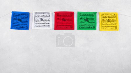 Téléchargez les photos : Drapeaux de prière bouddhistes tibétains colorés avec mantras par le Népal sur un fond gris, espace de copie, vue de dessus. Drapeaux de prière tibétains ont cinq couleurs représentant les éléments ou les énergies dans la nature - en image libre de droit