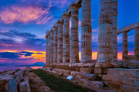 Beautiful sunset sky and ancient ruins of temple of Poseidon, cape Sounio, Aegean sea coast, Greece. Travel destination of Athens area, important center of ancient Greek religion for Olympian Greek