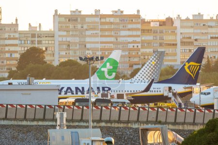 Foto de Jul 13,2023 - Lisboa, Portugal. Transavia, Ryanair y Vueling aeronaves en puestos de avión del aeropuerto en la noche de verano. Pasajeros que abordan el avión Ryanair - Imagen libre de derechos