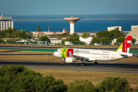 Photo for Jul 23, 2023 - Lisbon, Portugal. Air Portugal or TAP airplane on runway of Humberto Delgado airport, known as Lisbon airport, on sunny day. Residential area and river Tagus in background. - Royalty Free Image