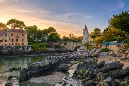 Colorful sunset over Museum of Conde de Castro Guimaraes, Cascais, Portugal. Beautiful building in picturesque location, next to tidal pool, sandy beach, rocky shores and bridge, stylized as Manueline