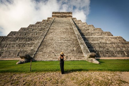 Woman wearing hat and black dress (back view, unrecognized) in front of the Chichen-Itza pyramid in Yucatan, Mexico