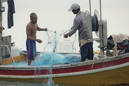 Photo for Hai fishermen untangle fishing net in the boat in Koh Tao, Thailand - Royalty Free Image