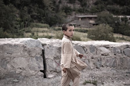 Téléchargez les photos : Garçon pakistanais sur la route dans la région montagneuse, Pakistan - en image libre de droit