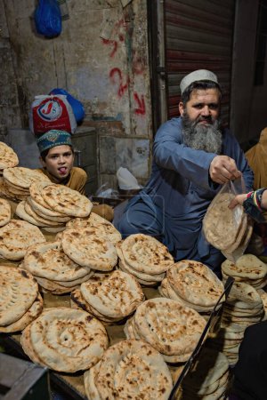 Téléchargez les photos : Pashtun man selling local bread on the Qissa Khwani Bazaar in Peshawar, Pakistan - en image libre de droit
