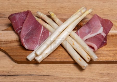 White asparagus with fresh ham on a wooden plate