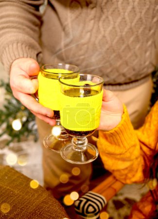 Foto de Dos copas de vino caliente en las manos de un hombre y una mujer, de cerca. Concepto de Navidad. - Imagen libre de derechos
