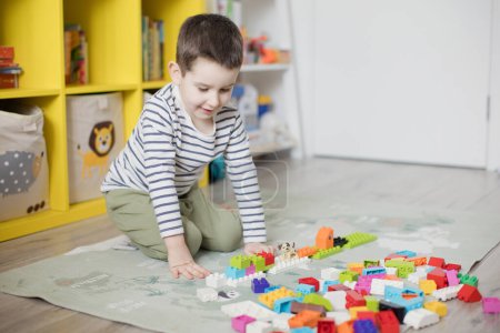 Foto de Caucásico niño jugando con bloques de juguete de colores en su habitación. - Imagen libre de derechos