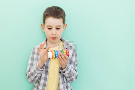 Téléchargez les photos : Caucasian preschool boy with arithmetic math learning toy on a light green background with copy space - en image libre de droit