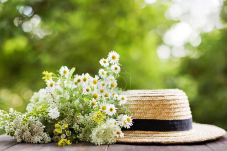 Téléchargez les photos : Chapeau de paille plaisancier et bouquet de fleurs sauvages sur une table en bois sur fond vert - en image libre de droit