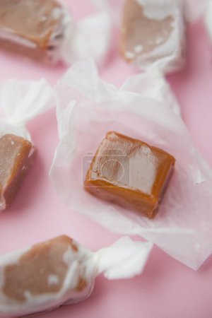 Téléchargez les photos : Caramel candy fudge in paper wrapping on a pink background - en image libre de droit